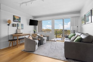A modern living room with a sofa, armchairs, a coffee table, and a TV.