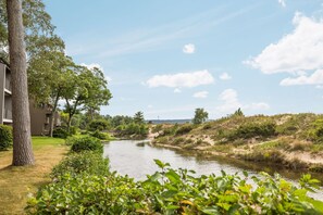 A river flowing through a landscaped area with trees and a building on the left.