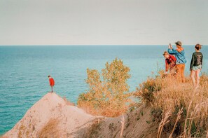 A coastal landscape with a person standing on a cliff overlooking the sea.