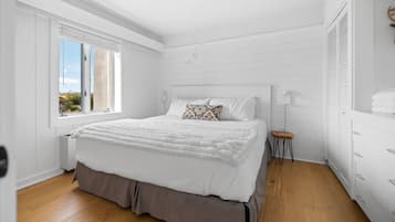 Une chambre à coucher avec un grand lit, une fenêtre, une table de chevet et une armoire.