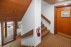 A staircase with a fire extinguisher mounted on the wall, a wooden door with the number 4, and a window with a view of the outdoors. - GOOD VIBES LAKEFRONT CONDO (Glen Arbor)