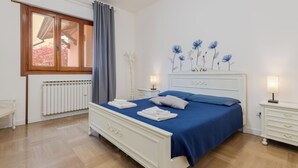 A bedroom with a bed, bedside tables, a radiator, a window with curtains, and a wall decoration. - Marco Polo Airport GATE 2 Comfy 1+1BR Apt with Venice Access (Venezia)