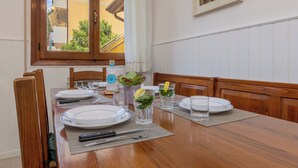 A dining table set with plates, glasses, and cutlery, a potted plant, and a window with a view of greenery. - Marco Polo Airport GATE 2 Comfy 1+1BR Apt with Venice Access (Venezia)