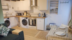 Cuina compacta amb rentadora, microones, forn i zona menjador amb taula per a dues persones.