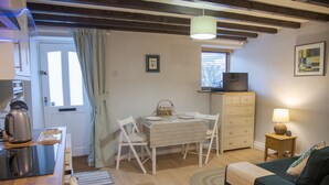 Habitació acollidora amb taula de menjador, cadires, sofà, televisió i làmpada.