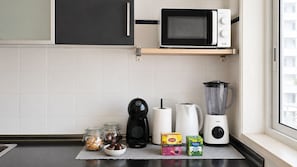 A kitchen with a microwave, coffee maker, blender, and jars of food on the counter. - Room-charming Lisbon Apartment in Quiet (Lisbon)