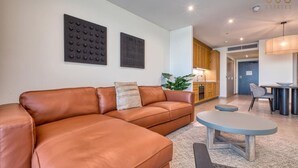 Een moderne woonkamer met een leren bank, een ronde salontafel en een eethoek met een tafel en stoelen.