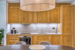 A modern kitchen with wooden cabinets, a stainless steel sink, and a round table with chairs. - Spacious 1BR Retreat | Luxury + Scenic Terrace (Rabat)
