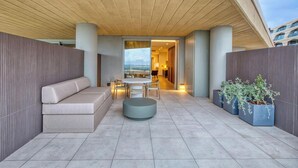 A modern outdoor seating area with a sofa, round table, and chairs, a potted plant, and a view of the sea. - Unwind in Style, Luxury Apartment w/ Scenic Views (Rabat)