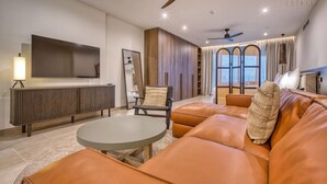A modern living room with leather sofas, a round coffee table, a TV mounted on the wall, and a ceiling fan. - Unwind in Style, Luxury Apartment w/ Scenic Views (Rabat)