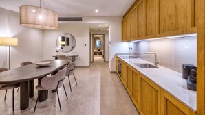 A modern kitchen with wooden cabinets, a large island with a sink, and a dining area with a round table and chairs. - Unwind in Style, Luxury Apartment w/ Scenic Views (Rabat)
