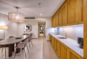 Eine moderne Küche mit Holzausbau, einer großen Kochinsel mit Spüle und einem Essbereich mit rundem Tisch und Stühlen.