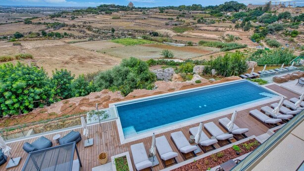 A rooftop pool with lounge chairs and a view of the surrounding landscape.