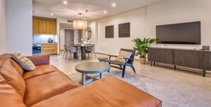 A modern living room with a leather sofa, a dining table with chairs, a TV, and a kitchen in the background. - Relax & Recharge | Hammock, Terrace, full Comfort (Rabat)