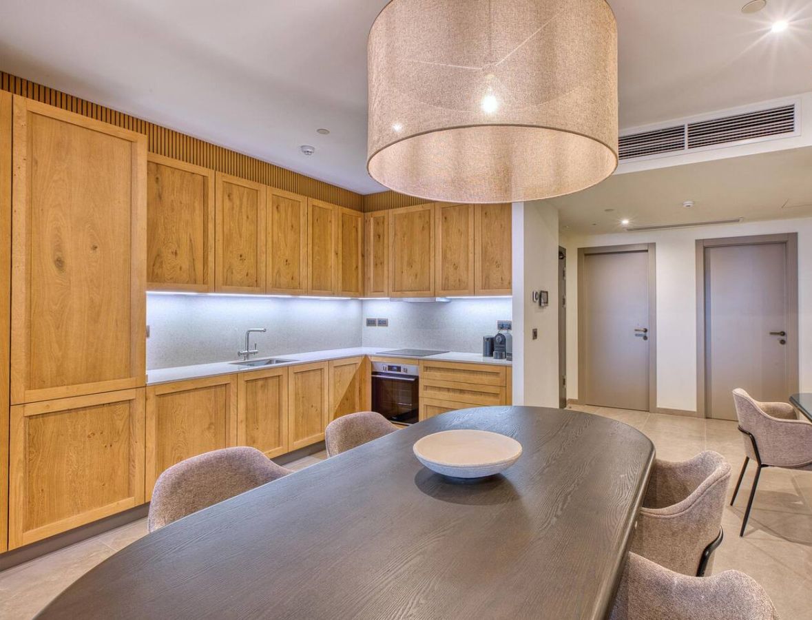 Une cuisine moderne avec des meubles en bois, une table à manger et un luminaire suspendu.