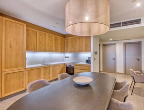 A modern kitchen with wooden cabinets, a dining table, and a pendant light. - Relax & Recharge | Hammock, Terrace, full Comfort (Rabat)