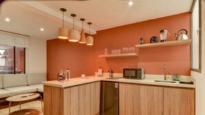 A modern kitchen with wooden cabinets, a built-in dishwasher, a microwave, and a coffee machine. There is a seating area with a sofa and a round table. - w Beautiful 1BR Retreat in Vibrant Zona T (Bogotá)