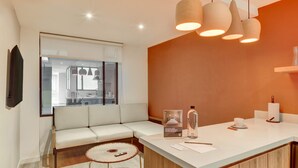 A modern hotel room with a sofa, a small round table, a counter with a sink, and pendant lights. - w Beautiful 1BR Retreat in Vibrant Zona T (Bogotá)