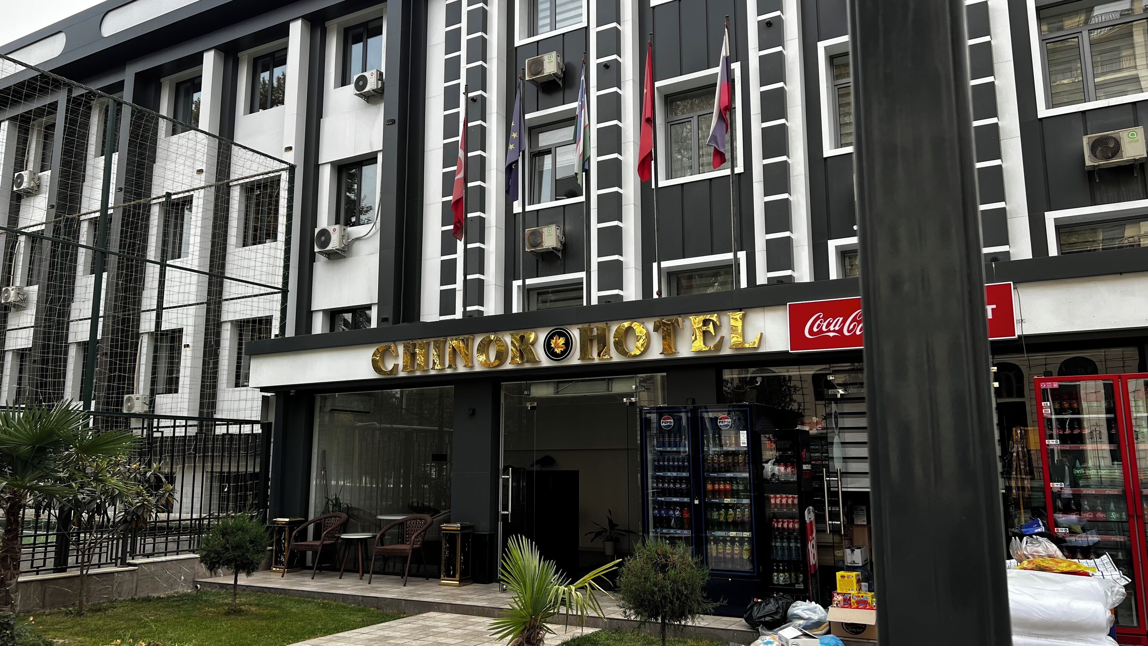 A hotel with a modern facade, featuring a Coca-Cola sign and multiple flags.