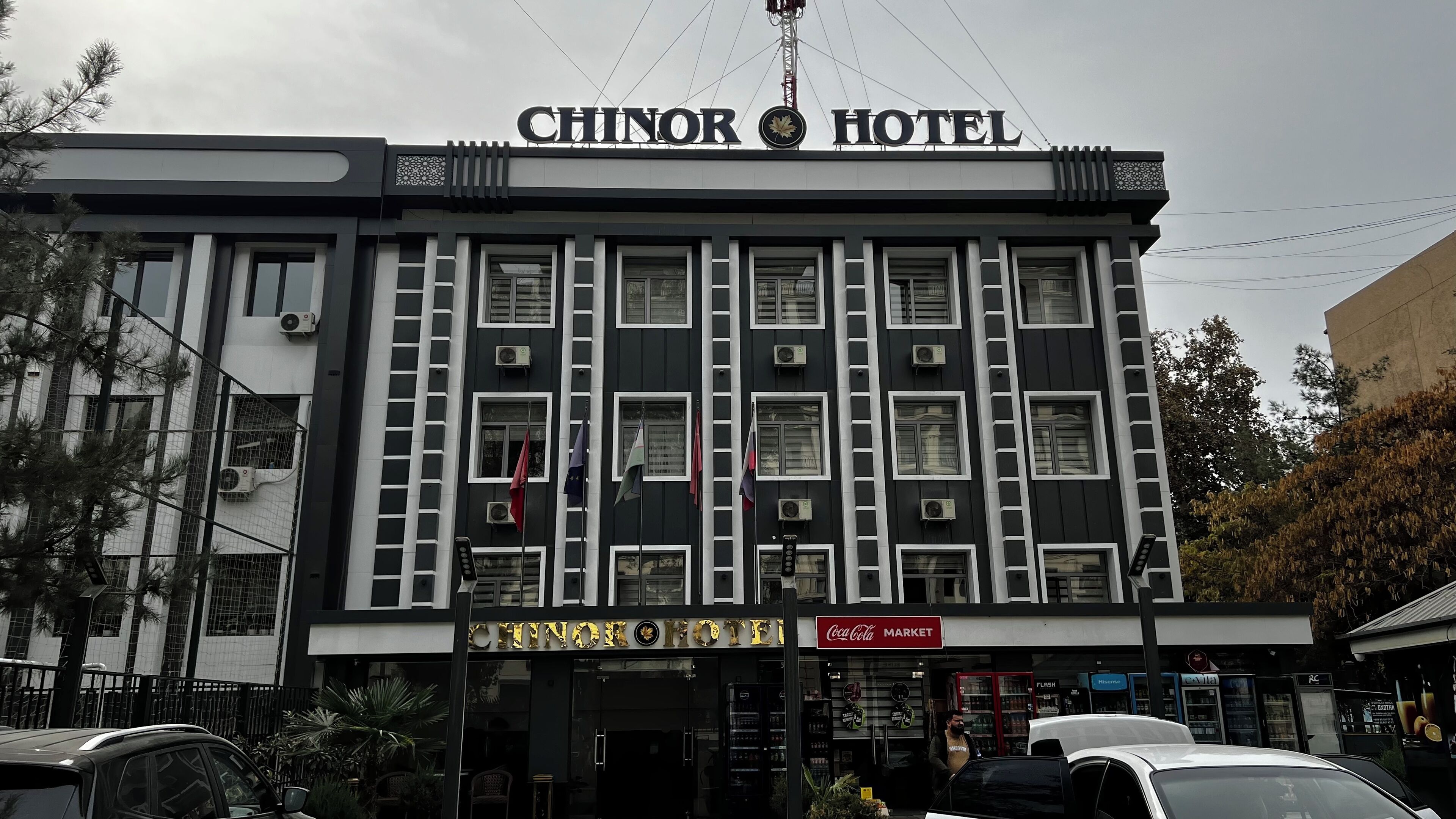 Exterior del hotel Chinar con un cartel de Coca Cola Market debajo.