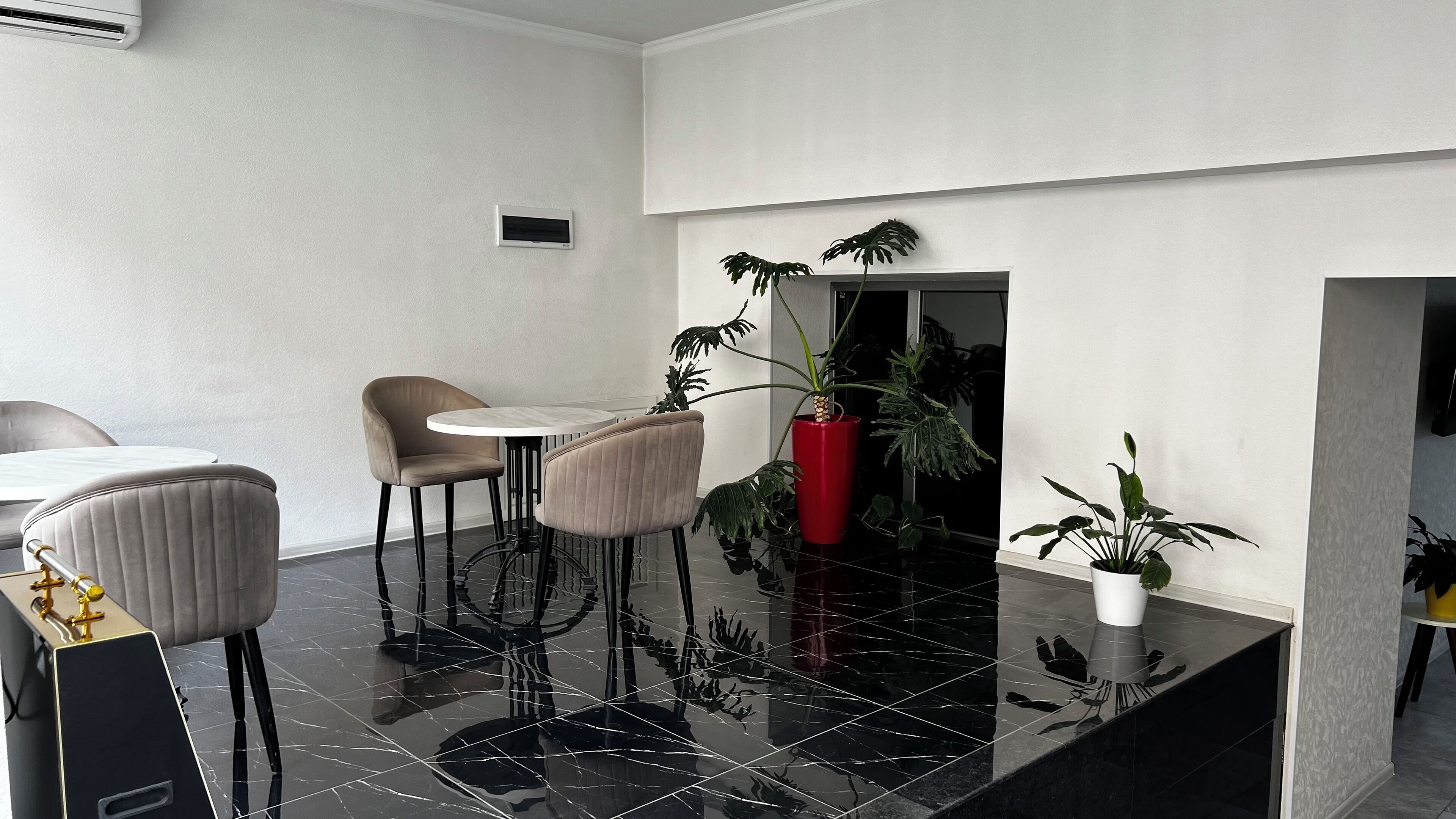 A modern dining area with a polished black floor, two round tables, and four upholstered chairs.