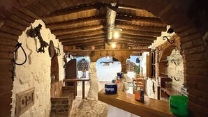 Ein rustikales Interieur mit Steinboden, Holzbalken und einer Bar mit einem Pepsi-Kühler.