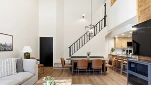 A spacious living area with a dining table, sofa, and a staircase leading to an upper level. - Giant Steps 30 Ski in/Ski out (Brian Head)