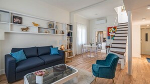 A modern living room with a sofa, coffee table, and a dining area with chairs and a table. - Apartments Florence - Blumberg (Firenze)