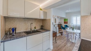 A modern kitchen with a marble countertop, white cabinets, and a built-in oven. - Apartments Florence - Blumberg (Firenze)