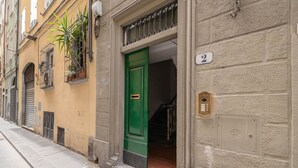 A building with a green door, a number '2' sign, and a small window with plants. - Apartments Florence - Blumberg (Firenze)