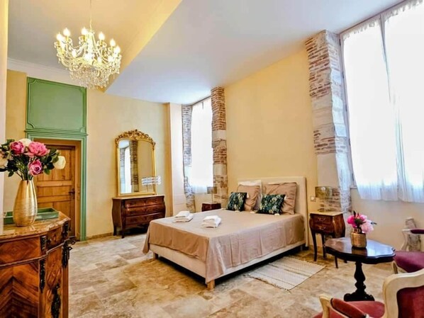 A bedroom with a large bed, a chandelier, a dresser, a mirror, and a window with curtains. - Beautiful Romantic Suite with private terrace (Vicq-d'Auribat)