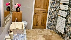 Casa de banho com lavatório de mármore, porta de madeira e painel de azulejos.