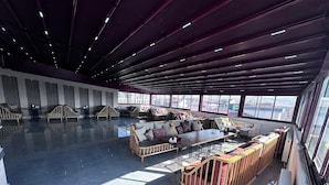 A spacious lounge area with modern furniture, large windows offering city views, and a high ceiling with exposed beams. - ELEGRAND HOTEL (Van)