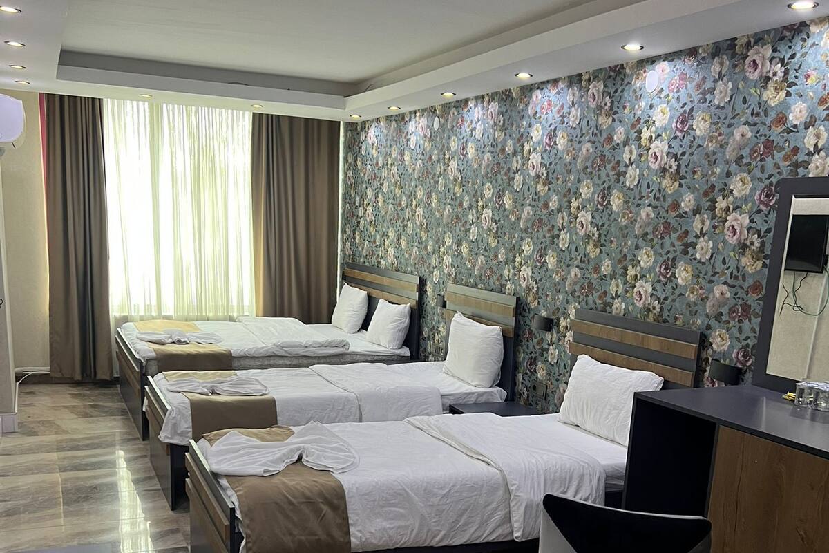 A hotel room with three beds, a desk, and a chair.