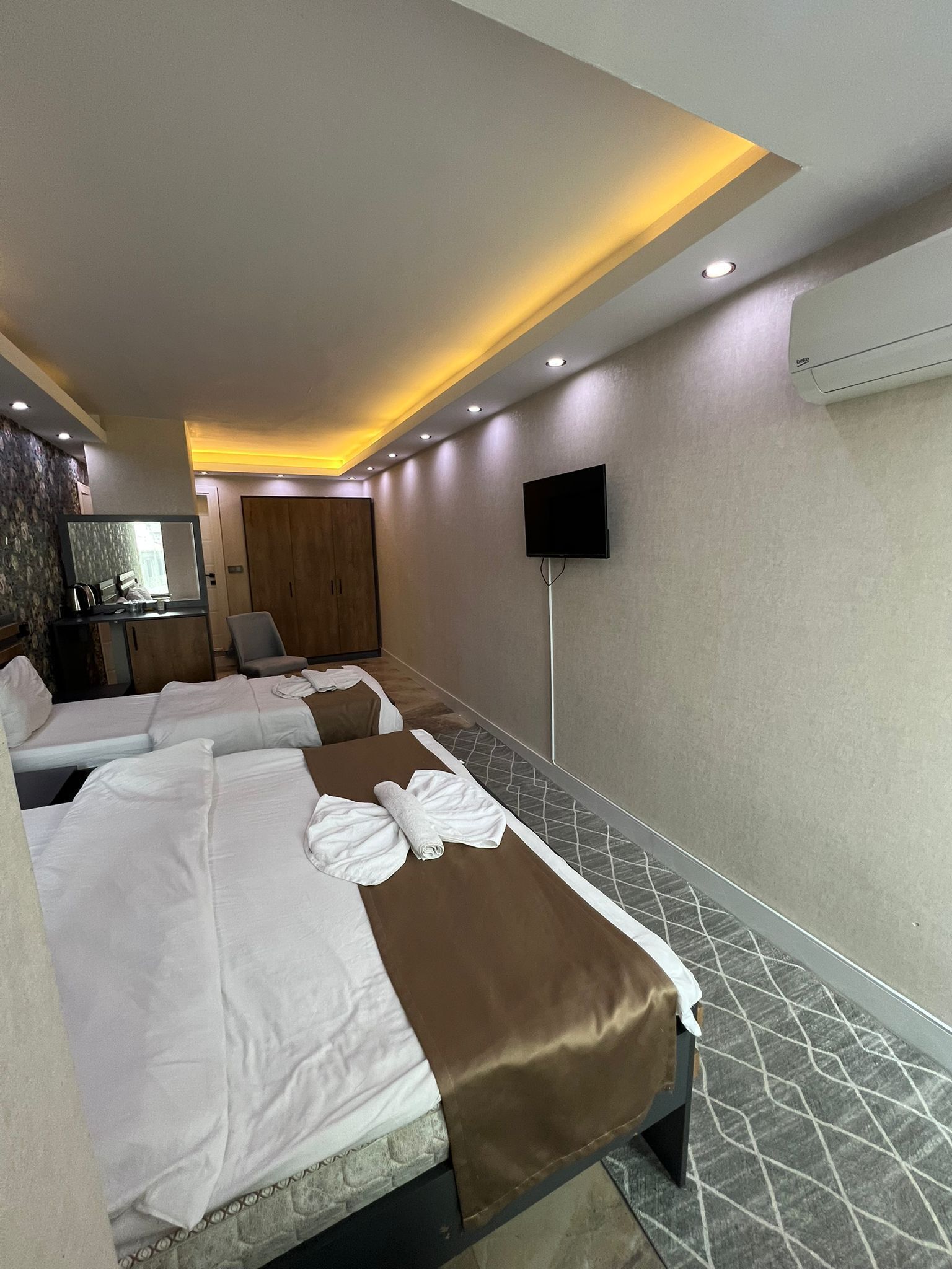 Habitación de hotel con dos camas, un televisor, un espejo y un armario.