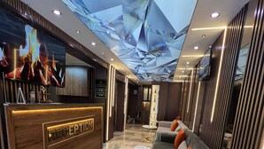A hotel lobby with a reception desk, seating area, and a ceiling with a geometric design. - ELEGRAND HOTEL (Van)