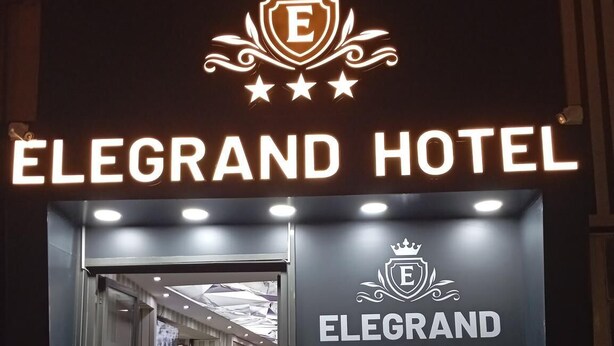 The entrance to the Elegrand Hotel with a prominent sign displaying the hotel's name and contact information. - ELEGRAND HOTEL (Van)