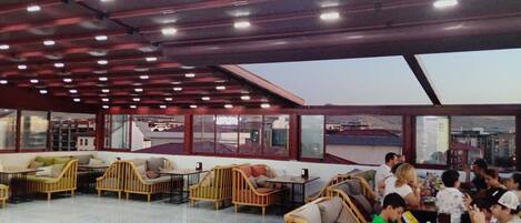 A spacious indoor area with multiple seating arrangements, including chairs and sofas, under a ceiling with numerous lights.