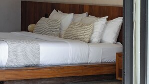 A bed with a wooden headboard, white bedding, and a wall with circular cutouts.