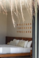 Una cama con cabecera de madera, ropa de cama blanca y una pared con recortes circulares.