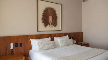 Quarto de hotel com cabeceira de madeira, cama com roupa de cama branca e uma obra de arte pendurada na parede.