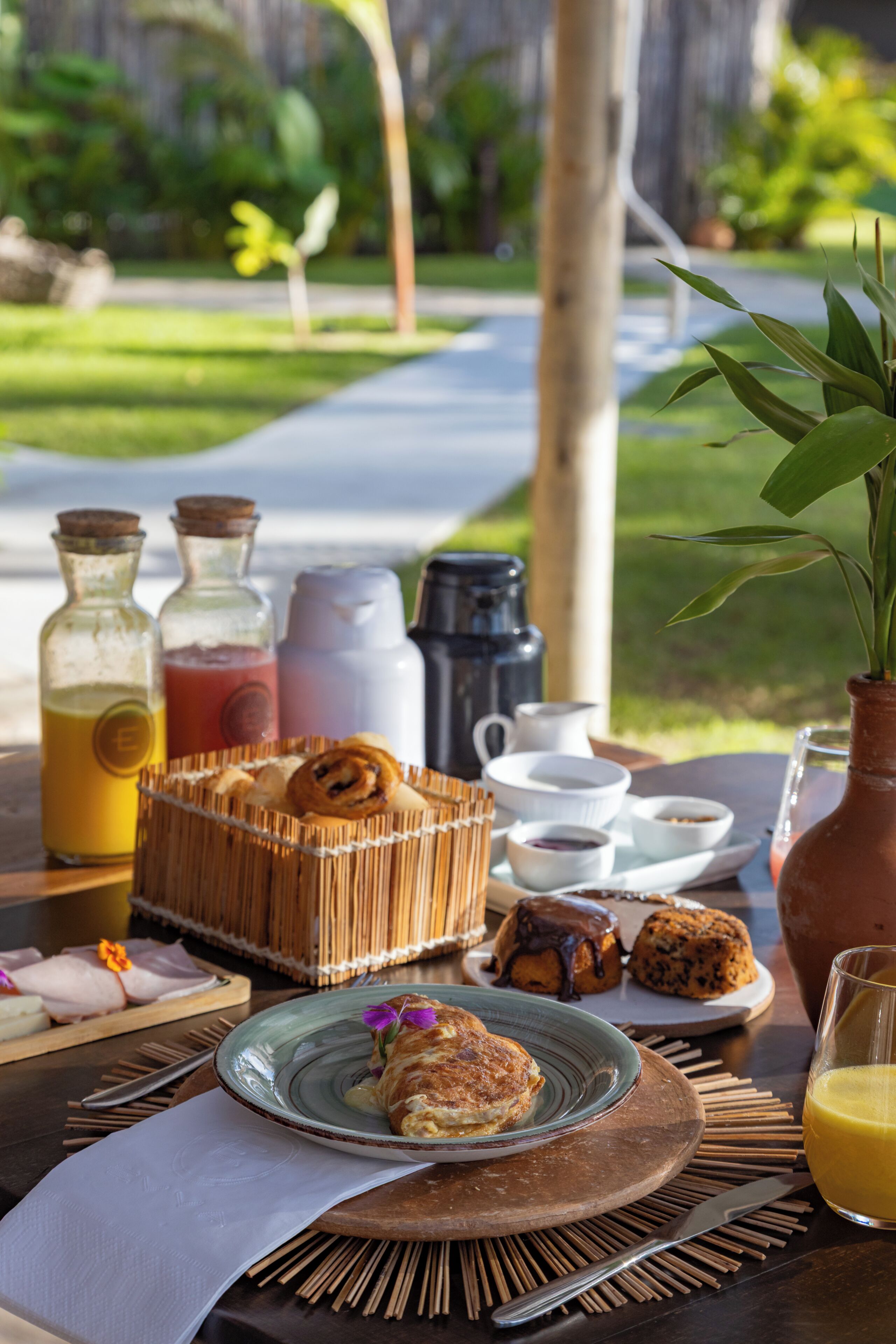Une table de petit-déjeuner avec une variété d’aliments, notamment des viennoiseries, une boisson aux fruits et des condiments.