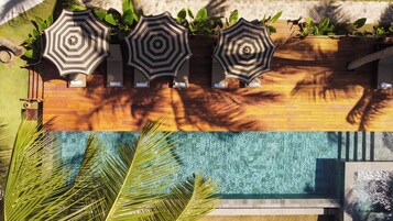 A pool area with three umbrellas, a wooden deck, and a clear swimming pool.