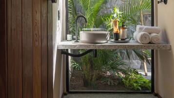 Un baño con pared de piedra, un lavamanos, un espejo y un inodoro.