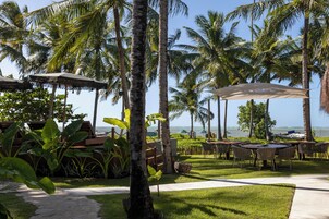 Un resort tropical con asientos al aire libre, palmeras y vista al océano.