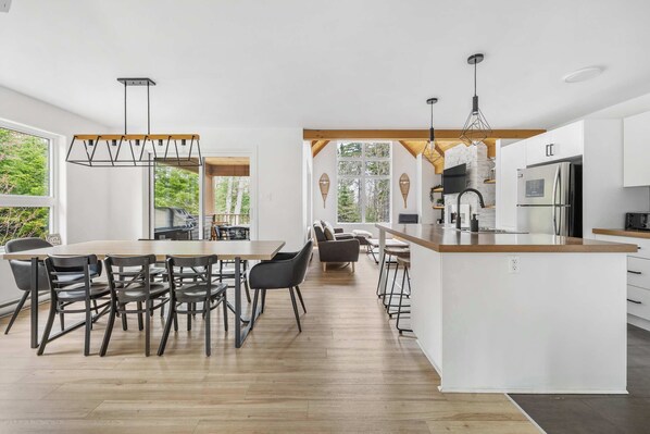Una cocina moderna con una isla central, suelo de madera e iluminación colgante.