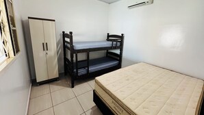 Quarto com cama beliche, uma cama de solteiro, guarda-roupa e ar condicionado.
