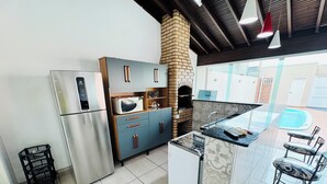 Uma cozinha moderna com eletrodomésticos de aço inoxidável, um forno de tijolos e um espaço bar com banquetas.