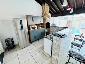 A modern kitchen with stainless steel appliances, a brick oven, and a bar area with stools. - Heated pool, air conditioning, Wi-Fi, near the park. (Olimpia)