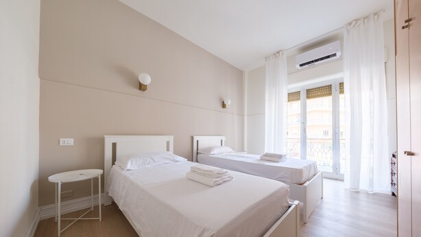 Ein Hotelzimmer mit zwei Betten, einem kleinen Tisch, einer Klimaanlage und Blick nach draußen.